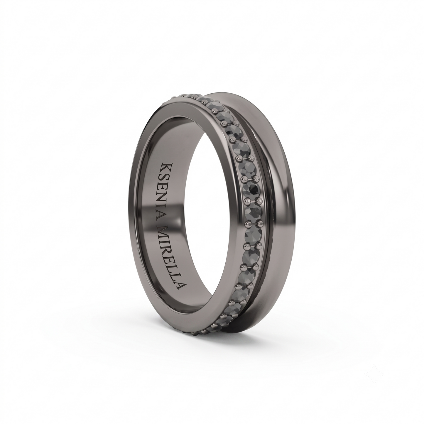 A dark gray metallic ring with a double row of small round clear stones on the front, featuring the engraved name 'Ksenia Mirella' on the inner band, shown on a white background.