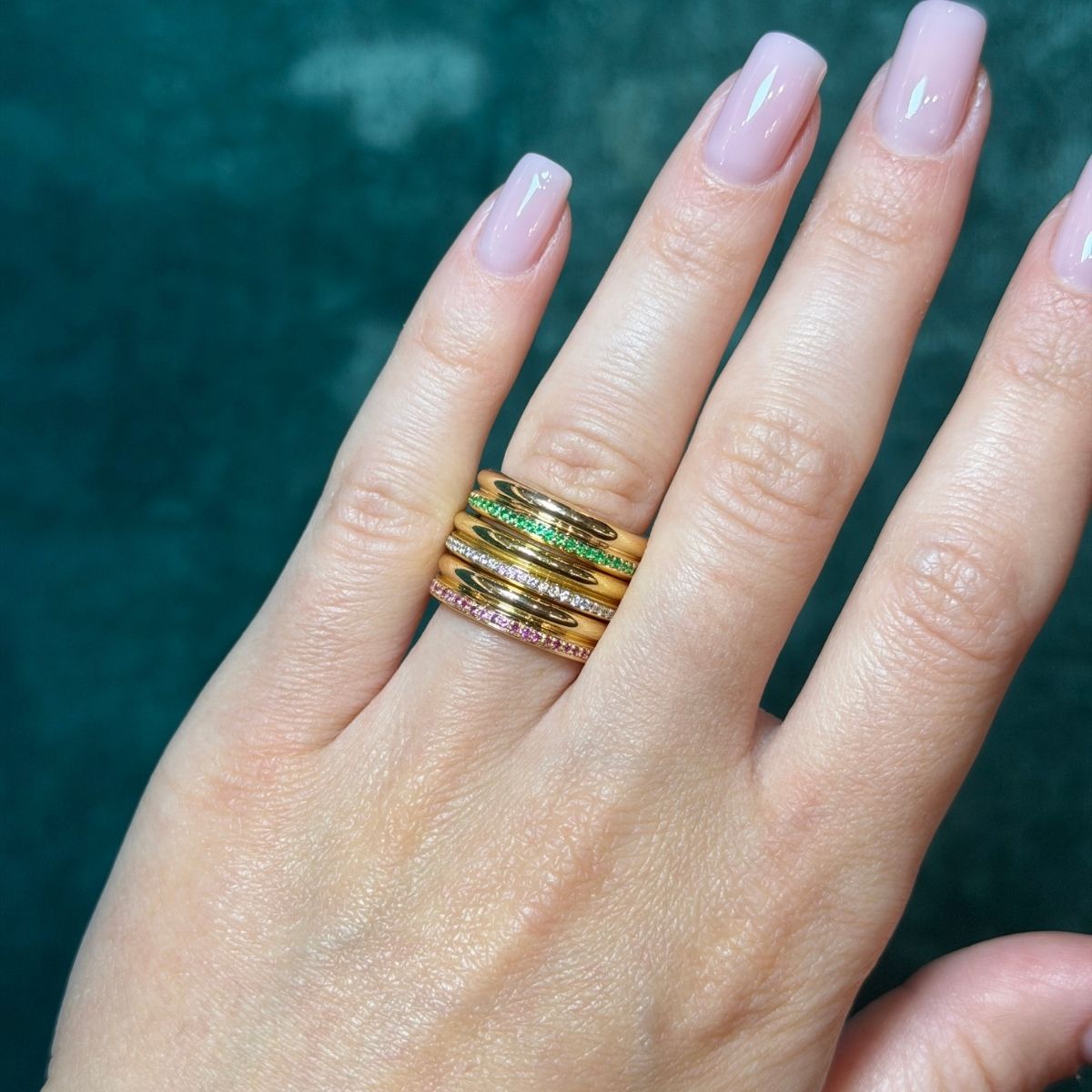 Hand wearing multiple gold rings with a blurred background perfect stacking rings
