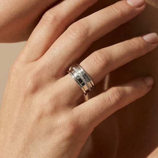 White Gold white diamond regina wide ring on a ladies hand on a neutral background 