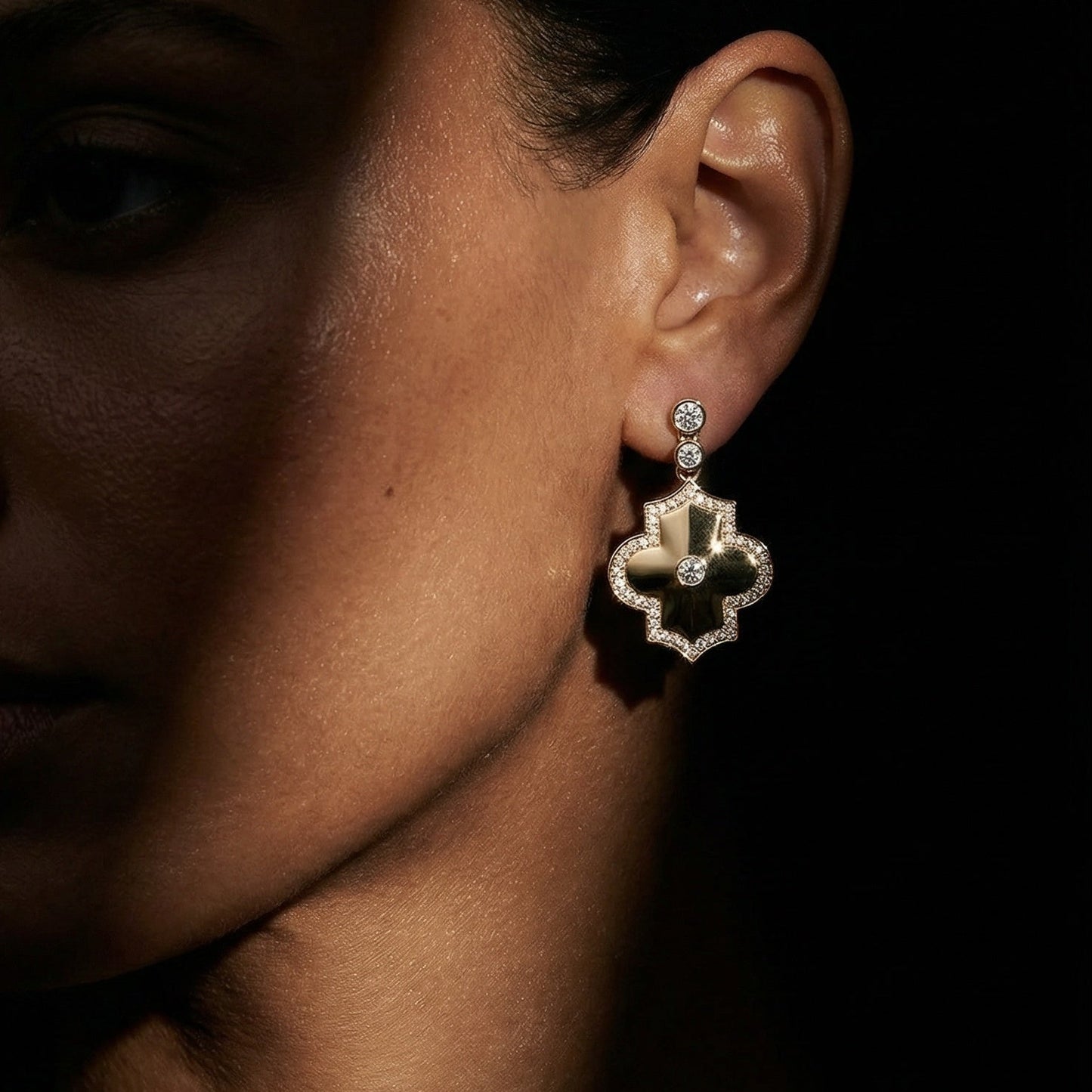 Close-up of a woman's ear wearing a decorative earring against a dark background