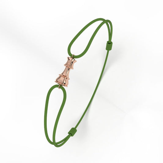 A rose gold bracelet with a geometric patterned clasp, attached to a green cord.