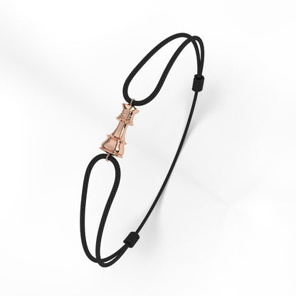 A rose gold bracelet with a geometric patterned clasp, attached to a black cord.