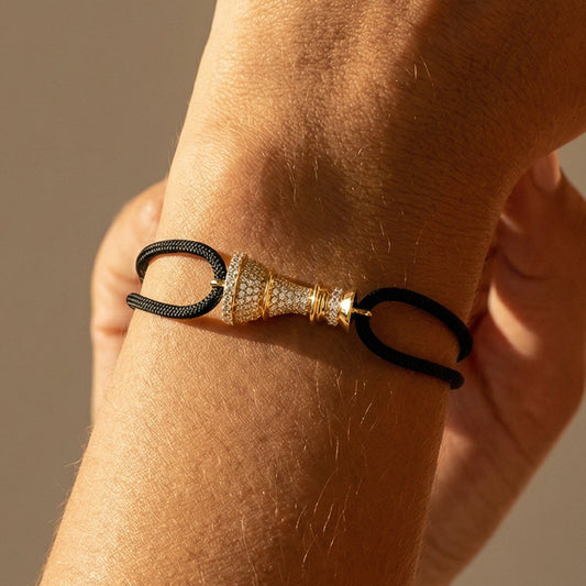 Close-up of a wrist wearing a Queen Chess bracelet on cord with a neutral background