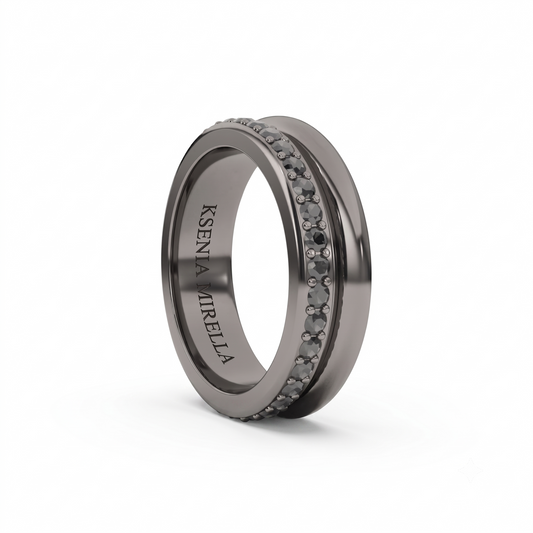 A dark gray metallic ring with a double row of small round clear stones on the front, featuring the engraved name 'Ksenia Mirella' on the inner band, shown on a white background.