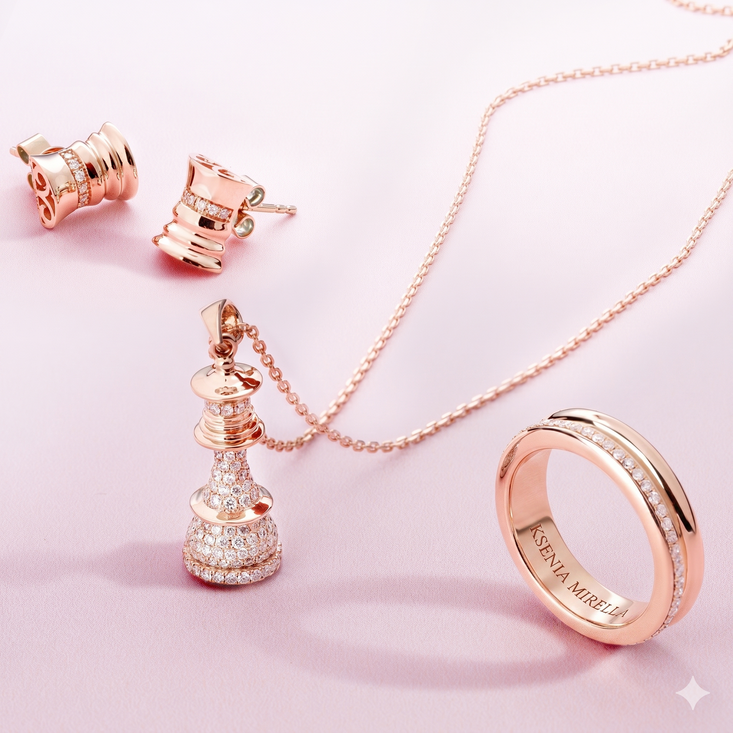 Rose gold jewelry set including earrings, necklace, and ring on a pink background from Ksenia Mirella Collection