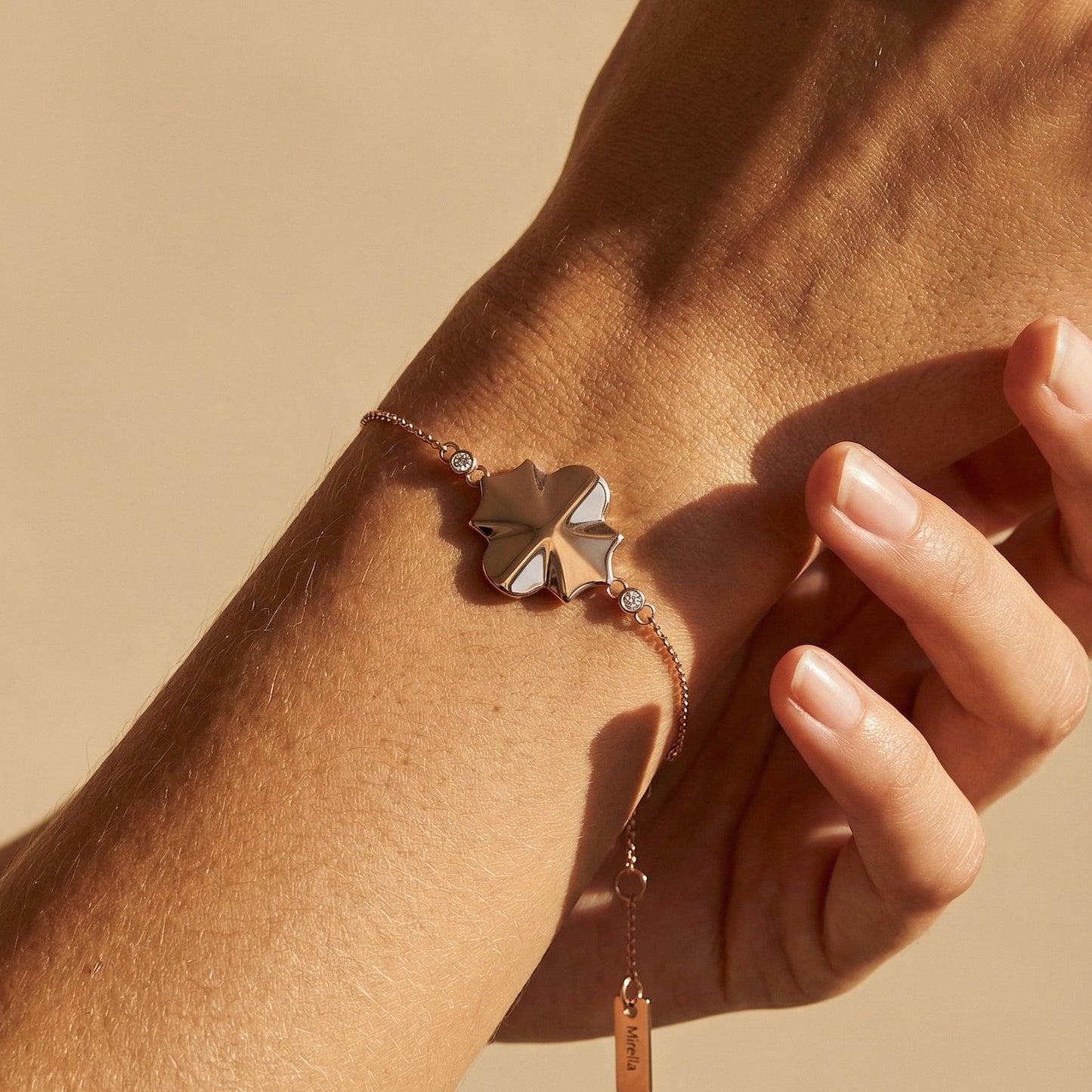 rose gold chain bracelet in the style of clover on a models hand 