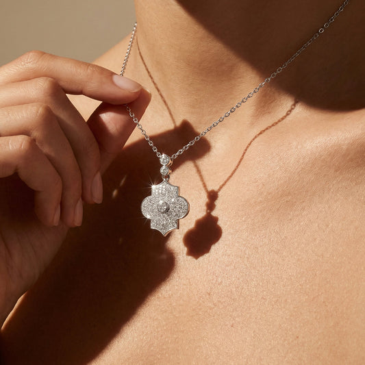 Close-up of a white gold diamond necklace with a pendant worn by a person.