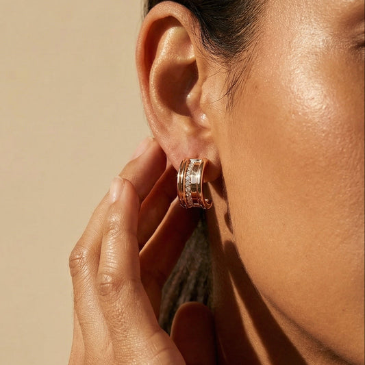 Close-up of a person wearing hoop earrings with a neutral background