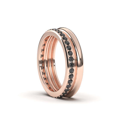A rose gold ring with black diamond accents on a white background.