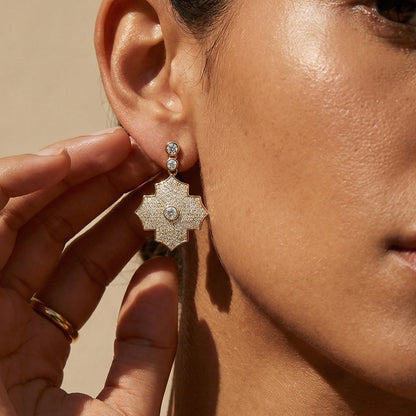 Close-up of a woman wearing a floral earring with a beige background