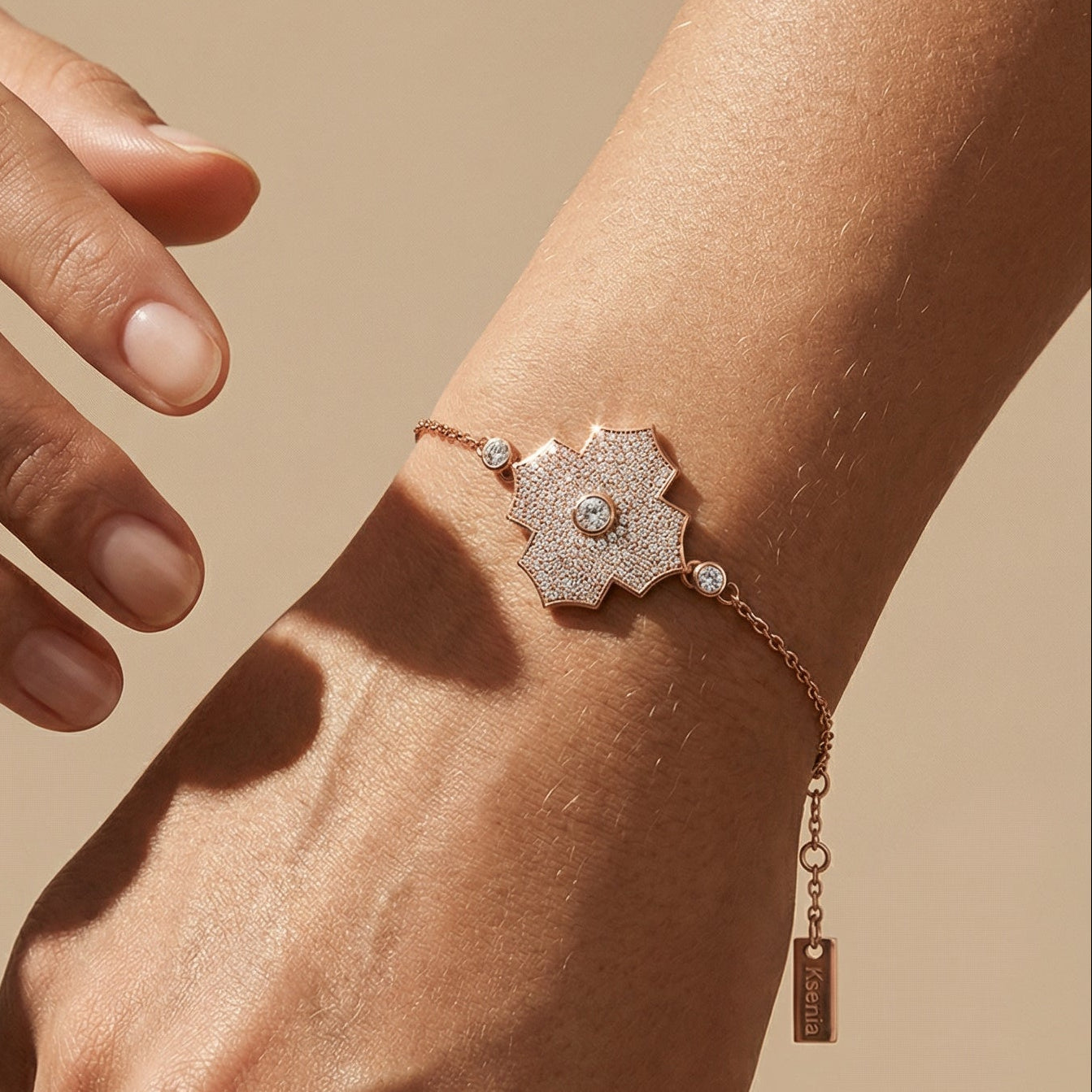 Rose gold bracelet with floral design on a wrist against a beige background