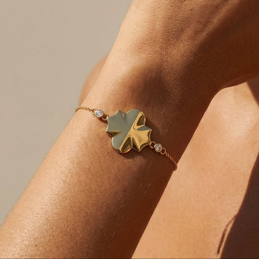 yellow gold white diamond chain bracelet in a shape of a clover worn by a model 
