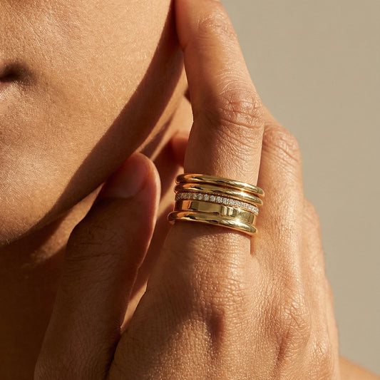 Close-up of a hand with gold rings on a neutral background