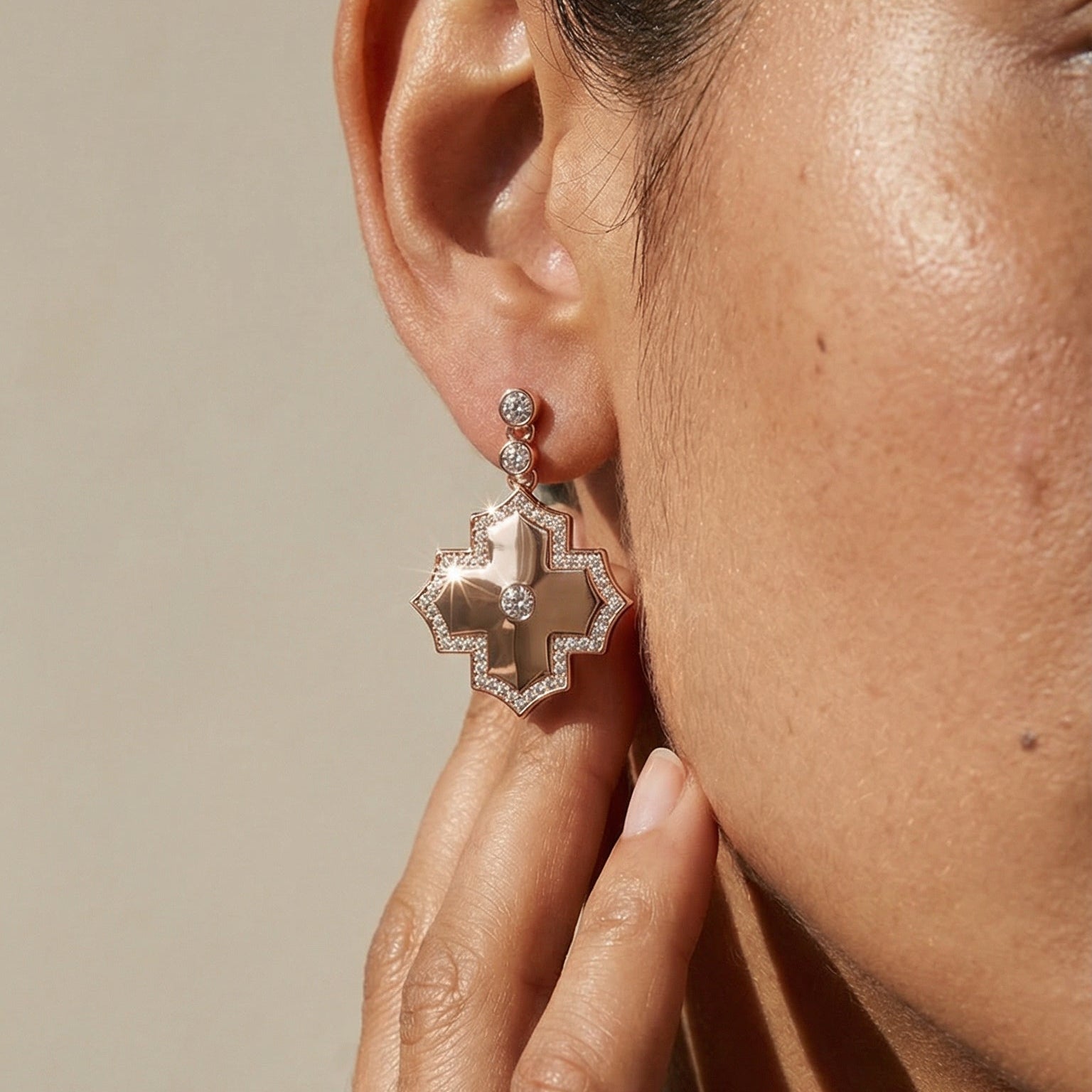 Close-up of a person wearing a decorative earring with a neutral background