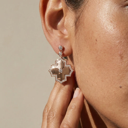 Close-up of a person wearing a decorative earring with a neutral background