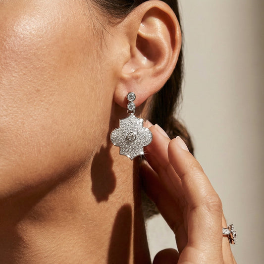 Close-up of a woman wearing sparkling silver earrings with a neutral background