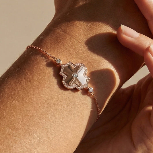 Close-up of a hand wearing a bracelet with a decorative clasp on a beige background