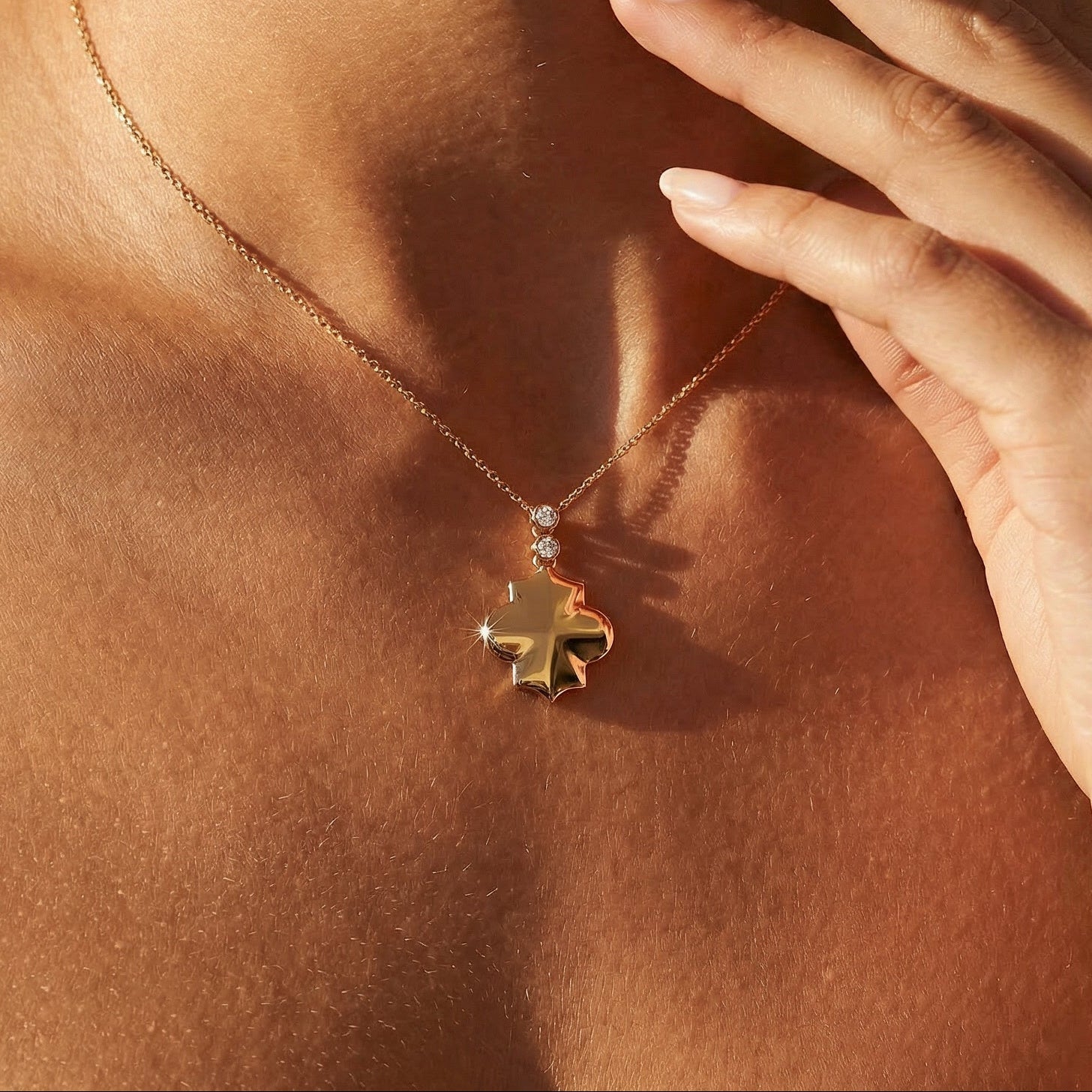 yellow gold white diamond clover style necklace on a chain worn by a model